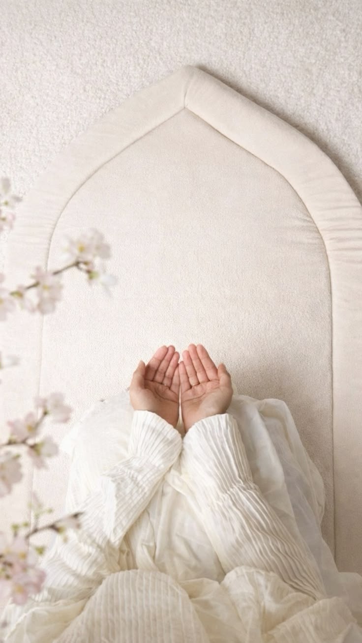 Hands raised in du'a on a prayer mat